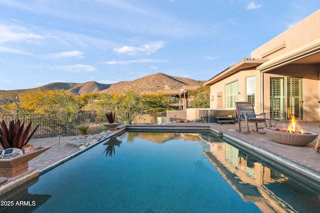 view of swimming pool featuring a patio, a mountain view, and a fire pit