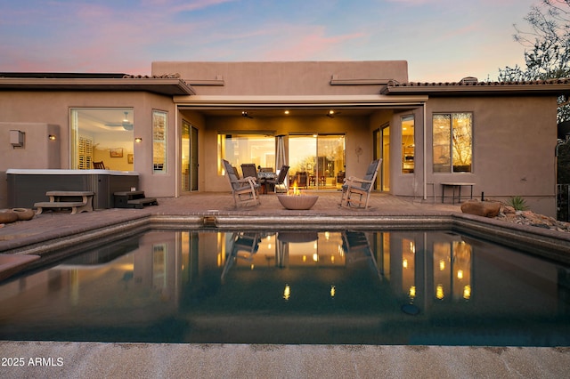 pool at dusk featuring a patio area and an outdoor fire pit