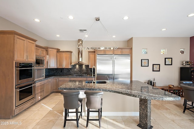 kitchen with built in appliances, sink, a breakfast bar area, and light tile patterned flooring