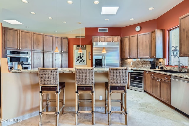 kitchen featuring appliances with stainless steel finishes, a skylight, beverage cooler, sink, and hanging light fixtures