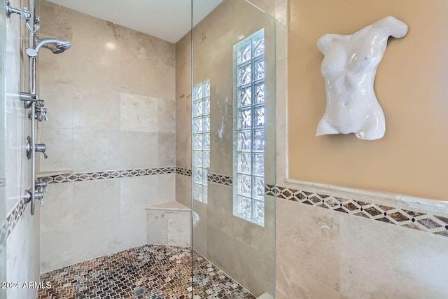 bathroom with tiled shower and tile walls