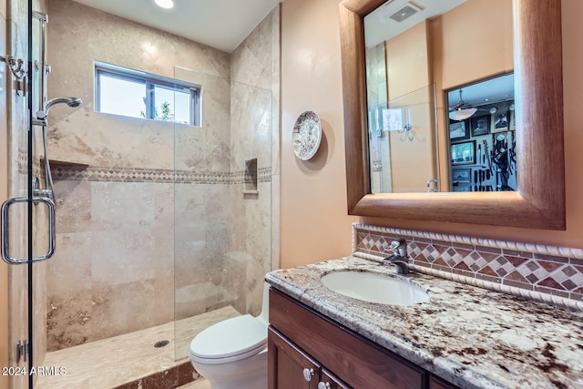 bathroom featuring decorative backsplash, vanity, a shower with shower door, and toilet