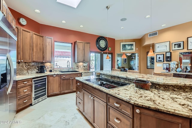 kitchen featuring black electric stovetop, sink, hanging light fixtures, stainless steel built in refrigerator, and beverage cooler