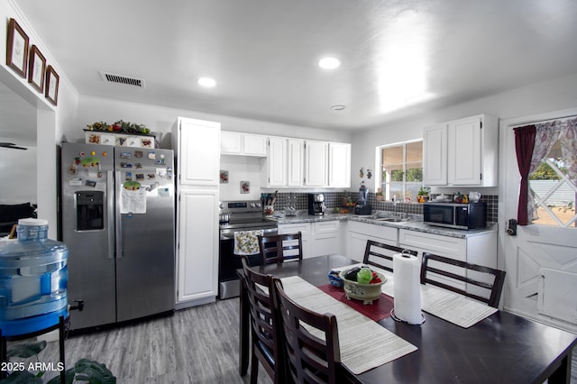 706 E Roosevelt Ave, Buckeye, AZ 85326 - kitchen featuring appliances with stainless steel finishes, white cabinets, a sink, light wood finished floors, and backsplash
