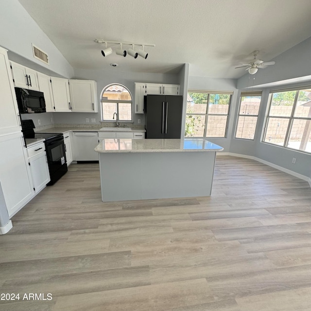 kitchen featuring white cabinets, light hardwood / wood-style floors, vaulted ceiling, and black appliances