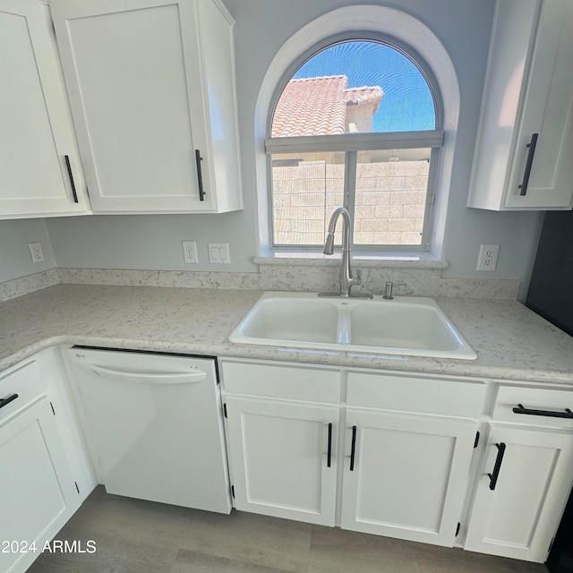 kitchen featuring light stone counters, white cabinets, white dishwasher, and sink