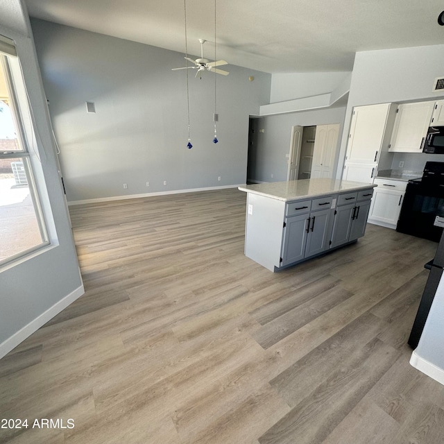 kitchen with white cabinetry, light wood-type flooring, black appliances, a center island, and ceiling fan