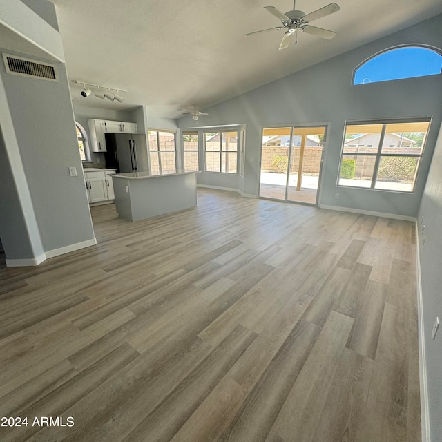 unfurnished living room with vaulted ceiling, ceiling fan, track lighting, and light hardwood / wood-style floors