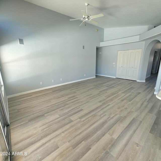 unfurnished bedroom with lofted ceiling, ceiling fan, light hardwood / wood-style flooring, and a closet