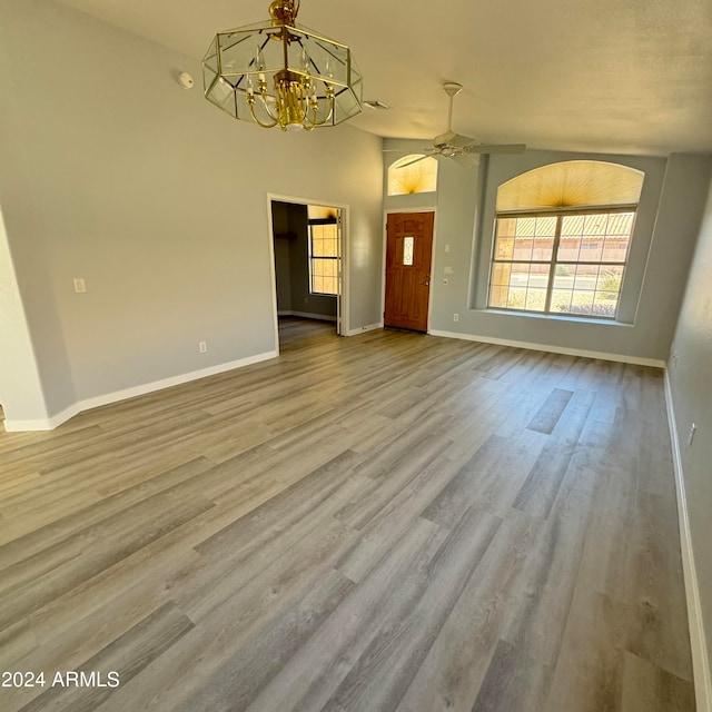 interior space featuring ceiling fan with notable chandelier, vaulted ceiling, and hardwood / wood-style flooring