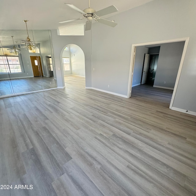 unfurnished room with ceiling fan, light wood-type flooring, and high vaulted ceiling