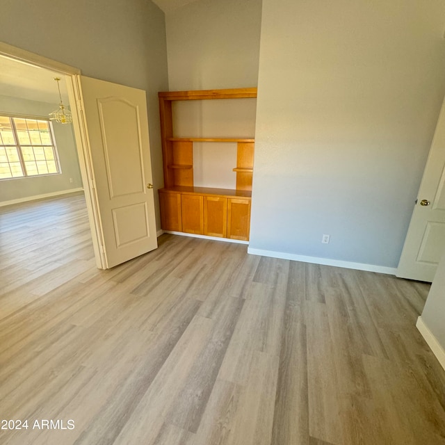 unfurnished bedroom with a chandelier, light hardwood / wood-style floors, and a high ceiling