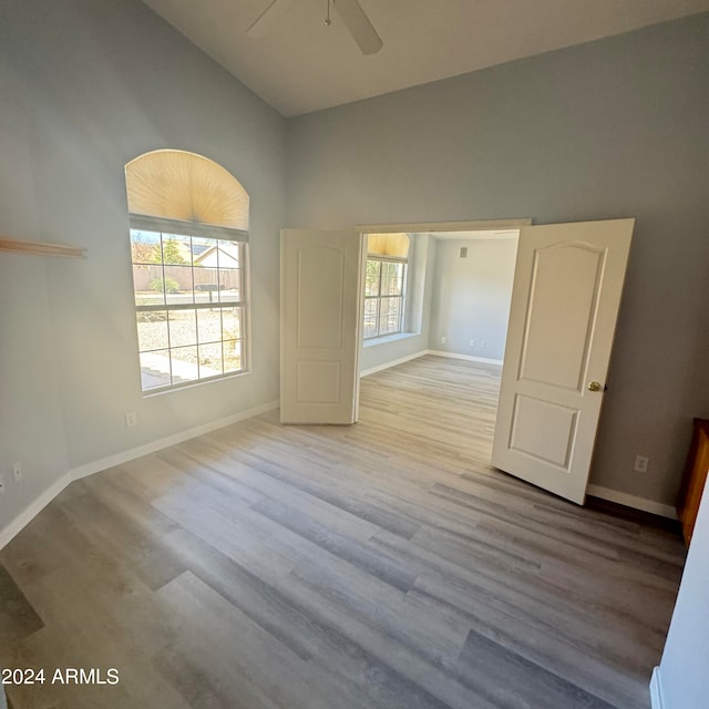 spare room featuring light hardwood / wood-style floors, vaulted ceiling, ceiling fan, and plenty of natural light