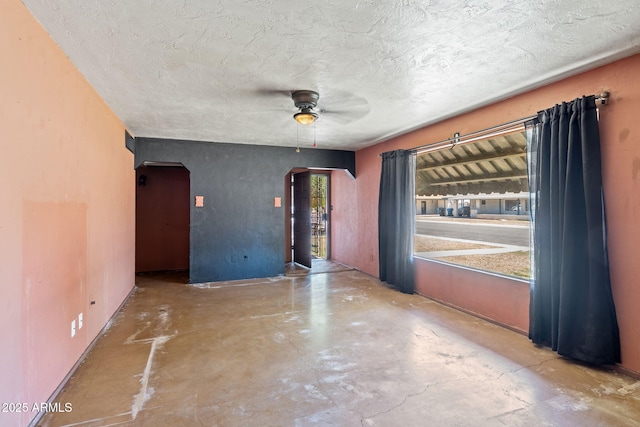 2020 W Marshall Ave, Phoenix, AZ 85015 - spare room with arched walkways, unfinished concrete flooring, a ceiling fan, and a textured ceiling