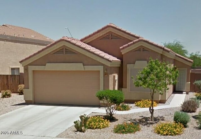 view of front facade with stucco siding, concrete driveway, an attached garage, fence, and a tiled roof