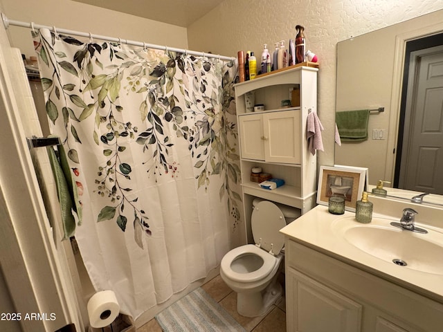 full bath featuring a textured wall, toilet, tile patterned floors, curtained shower, and vanity