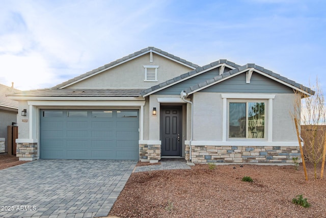 8332 N 54th Ln, Glendale, AZ 85302 - craftsman-style house featuring a tiled roof, stucco siding, decorative driveway, stone siding, and a garage