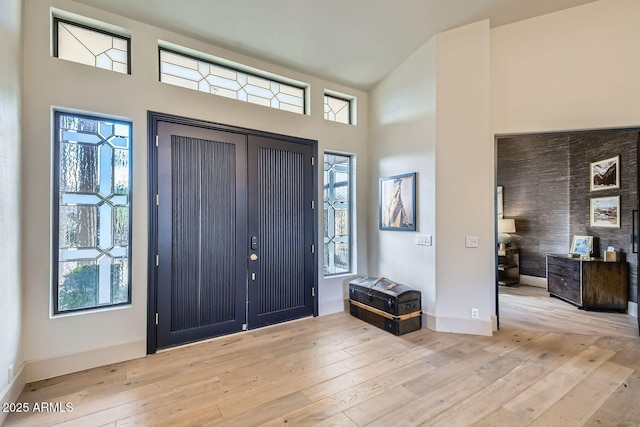 entrance foyer with light hardwood / wood-style flooring and high vaulted ceiling