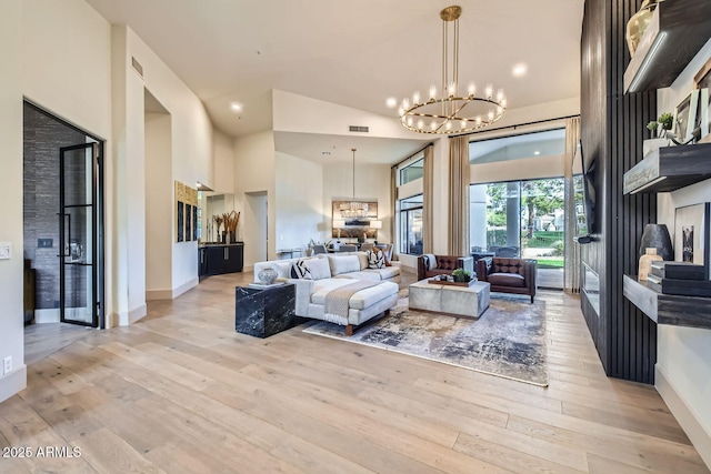 living room featuring an inviting chandelier, a towering ceiling, and light hardwood / wood-style flooring