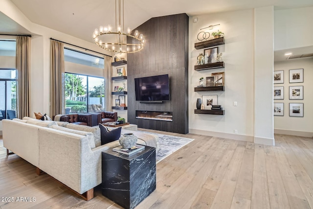 living room with plenty of natural light, vaulted ceiling, light hardwood / wood-style flooring, and a notable chandelier