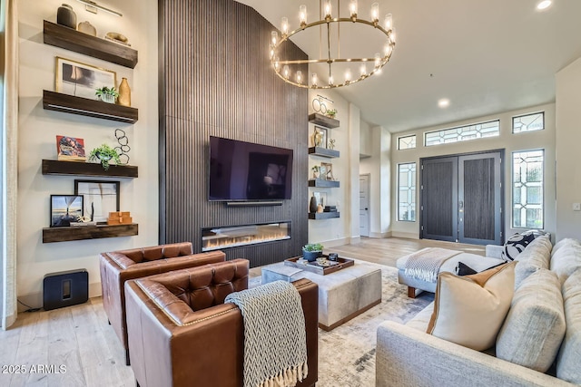 living room featuring a high ceiling, an inviting chandelier, and light hardwood / wood-style floors