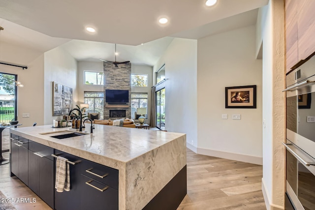 kitchen featuring a fireplace, plenty of natural light, sink, and a kitchen island with sink