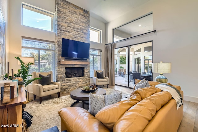 living room featuring a fireplace, light hardwood / wood-style flooring, and a high ceiling