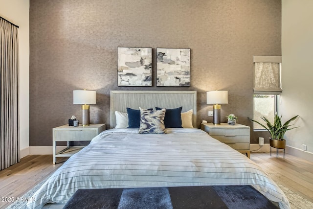 bedroom featuring a towering ceiling and light hardwood / wood-style flooring