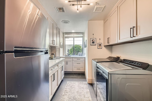 clothes washing area with tile patterned flooring, cabinets, sink, and independent washer and dryer