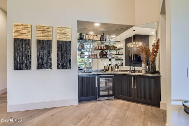 bar featuring decorative light fixtures, light hardwood / wood-style flooring, and beverage cooler