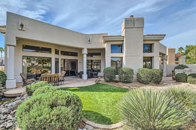 rear view of property featuring a lawn and a patio area