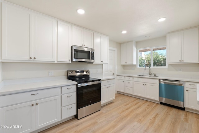 kitchen featuring light wood-type flooring, stainless steel appliances, white cabinetry, and sink