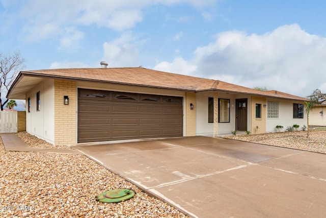 ranch-style house with brick siding, an attached garage, concrete driveway, and fence