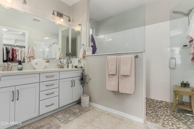 full bath with visible vents, double vanity, a stall shower, a sink, and a spacious closet