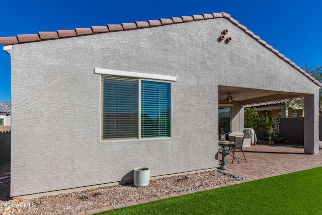 rear view of house featuring ceiling fan and a patio area