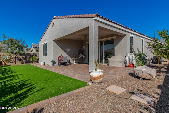 rear view of house with a tiled roof, stucco siding, a patio, a yard, and a ceiling fan