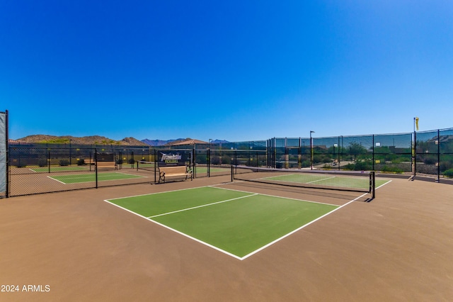 view of tennis court featuring a mountain view, community basketball court, and fence