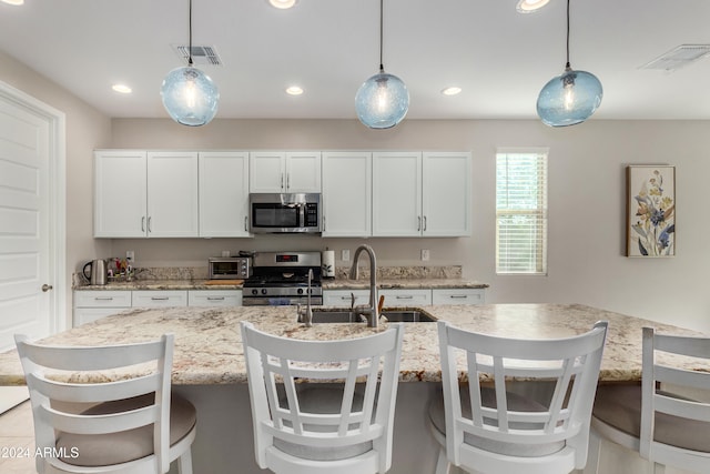 kitchen featuring hanging light fixtures, visible vents, stainless steel appliances, and a sink