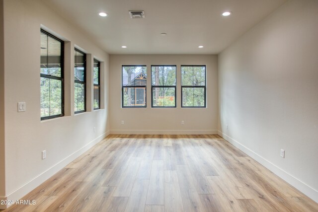 empty room with light wood finished floors, visible vents, and recessed lighting