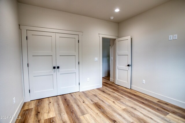 unfurnished bedroom featuring recessed lighting, a closet, light wood-style flooring, and baseboards