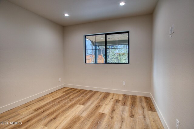 unfurnished room with recessed lighting, wood finished floors, and baseboards