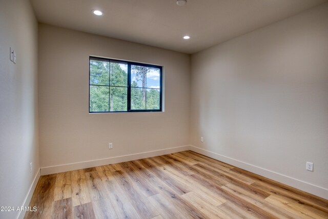 spare room featuring baseboards, light wood finished floors, and recessed lighting