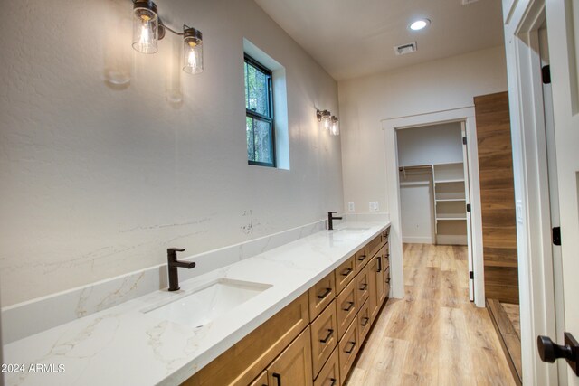 bathroom with double vanity, visible vents, a sink, and wood finished floors