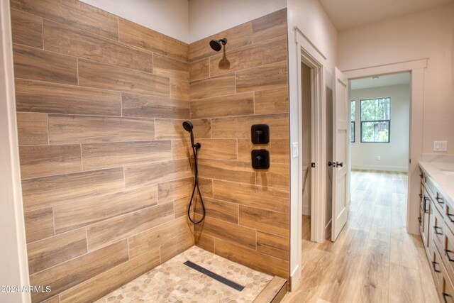 full bath with baseboards, a tile shower, wood finished floors, and vanity