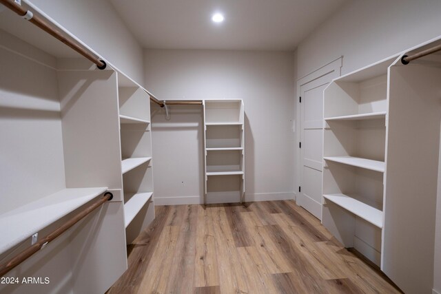 walk in closet with light wood-style floors