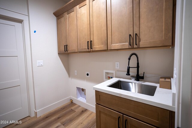 laundry area with cabinet space, hookup for a washing machine, electric dryer hookup, light wood-type flooring, and a sink