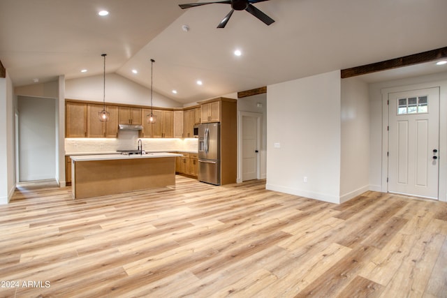 kitchen with light wood finished floors, open floor plan, light countertops, stainless steel refrigerator with ice dispenser, and a sink