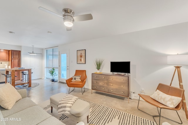 living room with baseboards, a ceiling fan, and finished concrete flooring