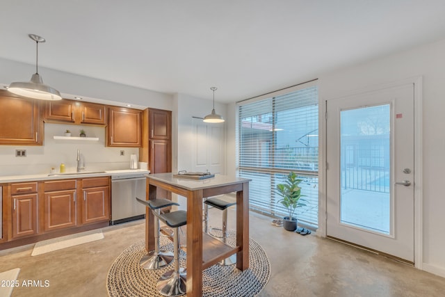 kitchen with brown cabinets, hanging light fixtures, a sink, and dishwasher