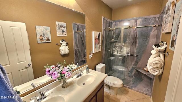 bathroom with toilet, tile patterned flooring, vanity, and tiled shower